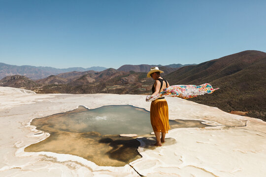 scarf blows in wind at the edge of a hot spring at hierve del agua