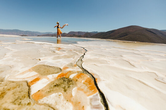 tourist with a blowing scarf walks the pools at hierve el agua oaxaca