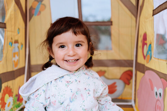 Happy toddler girl playing inside a toy house for kids