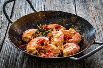 Fried prawns with thyme in cooking pan on wooden table
