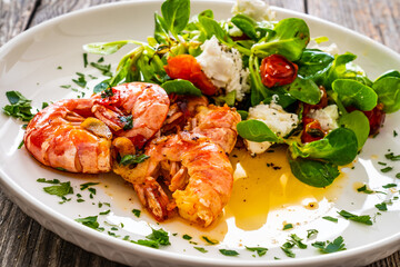 Fototapeta na wymiar Fried prawns with tomatoes and greens wooden table 