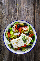 Fresh vegetable salad with feta cheese on wooden table

