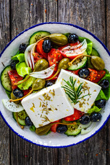 Fresh vegetable salad with feta cheese on wooden table
