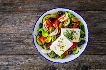 Fresh vegetable salad with feta cheese on wooden table
