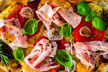 Pinsa Romana with cooked ham, mozzarella and vegetables on wooden table