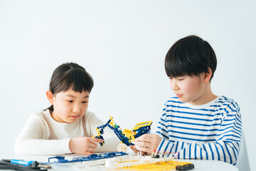 おもちゃのロボットで遊ぶ女の子と男の子 - obrazy, fototapety, plakaty