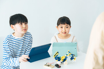 プログラミング教室でロボットの操作を学ぶ女の子と男の子