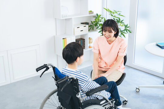車椅子に乗った男の子を診察する女性医療従事者
