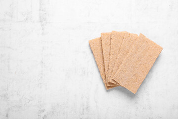 Fresh crunchy rye crispbreads on white textured table, top view. Space for text