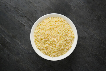 Bowl of tasty couscous on grey table, top view