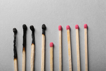 Burnt and whole matches on light grey background, flat lay. Stop destruction by breaking chain reaction concept