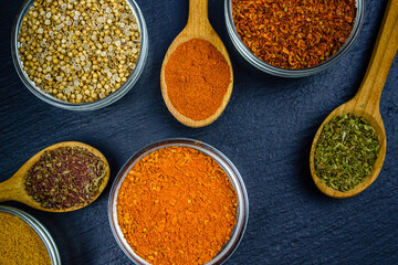 Spoons and bowls with oriental spices on a slate board. Top view