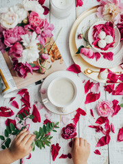 partial view of kid, drink in cup, sweet candies and flowers petals