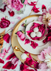 partial view of kid, drink in cup, sweet candies and flowers petals