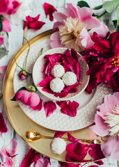 partial view of kid, drink in cup, sweet candies and flowers petals