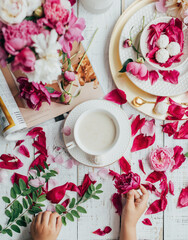 partial view of kid, drink in cup, sweet candies and flowers petals