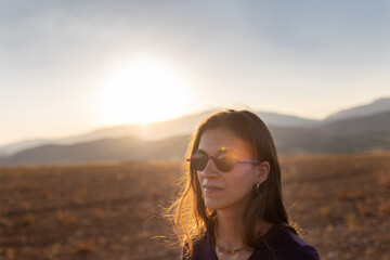 portrait of a beautiful young girl in glasses on a walk in the mountains. travel in the mountains at sunset.