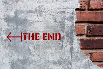 Old brick wall with text and direction to THE END, means final part of something, finish in period...