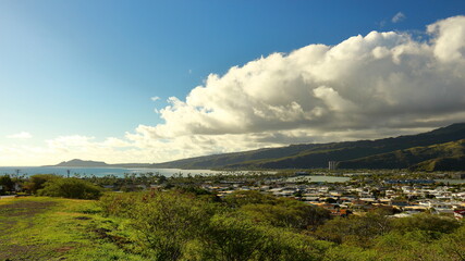Scenic panoramic view over Hawaii Kai suburbs and surrounding mountain landscape as clouds build on a sunny day, with Diamond Head in the distance. Near Honolulu, Hawaii.