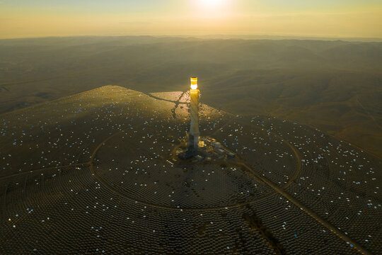 Hydroelectric Solar tower power station at sunrise in a desert landscape