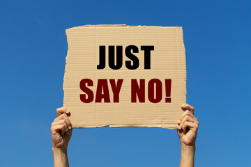Just say no text on box paper held by 2 hands with isolated blue sky background. This message board can be used as business concept to inform audience to refuse to do any bad thing.