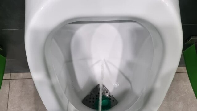 a stream of urine in a toilet bowl. a man pees in the toilet.