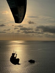 silhouette of a person on a parachute flying in a sky over Andaman sea - dreamy landscape view -...