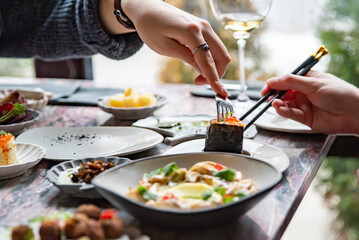 woman hand eating food in restaurant. wine, cheese, meat, vegetables and other appetizers on table