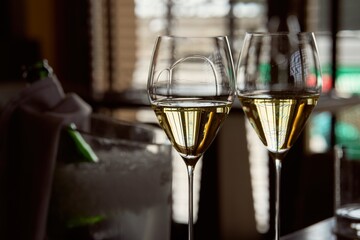 Couple of glass of champagne on table in elegant, fancy restaurant. Champagne bottle and bucket in background.