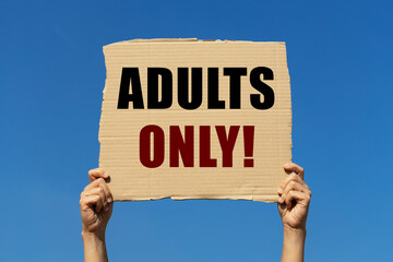 Adults only text on box paper held by 2 hands with isolated blue sky background. This message board can be used as business concept about adults only content.