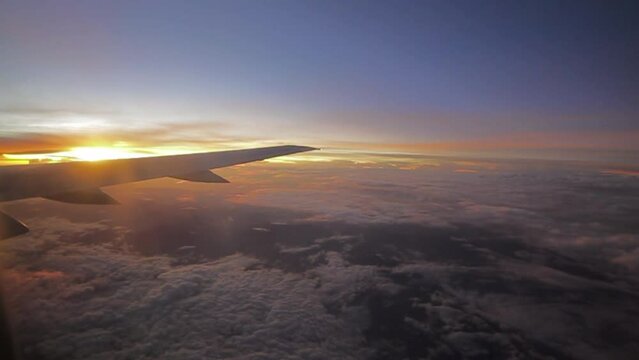 airplane fly onboard low clouds below sunrise peeking purple sky