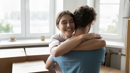 Happy young married couple of apartment buyers celebrating relocation, hugging with love, joy at...