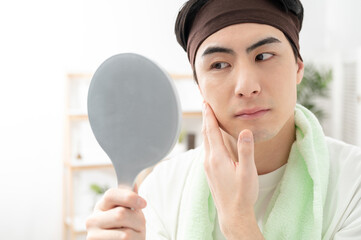 鏡で顔を確認する男性