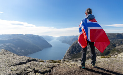 Woman with a waving flag of Norway on the background of nature - 577950445