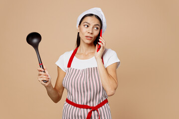 Young housewife housekeeper chef baker latin woman wear striped apron toque hat talk speak on...