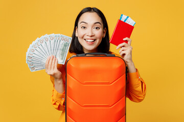 Young woman wear summer clothes hold passport ticket bag fan of cash money isolated on plain yellow...