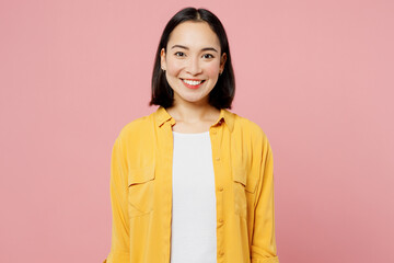 Young smiling happy fun cool cheerful student woman of Asian ethnicity wear yellow shirt white t-shirt looking camera isolated on plain pastel light pink background studio portrait. Lifestyle concept. © ViDi Studio