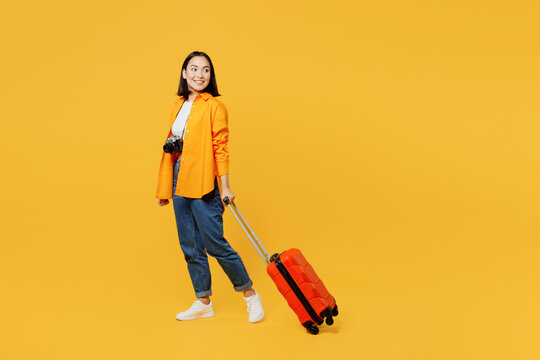 Young woman wear summer casual clothes walk go with suitcase bag look aside isolated on plain yellow background. Tourist travel abroad in free spare time rest getaway. Air flight trip journey concept.