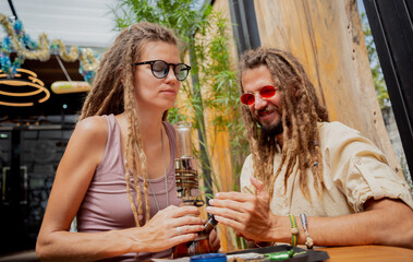 Hippie style couple smoking medical marijuana using a bong