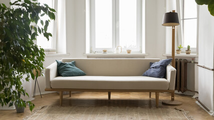 Small stylish pale sofa in modern Scandinavian interior of empty room with houseplant, torch,...