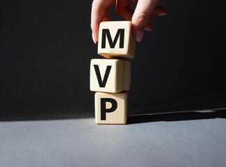 Naklejka premium MVP - Most Valuable Player symbol. Wooden cubes with words MVP. Businessman hand. Beautiful grey background. Business and MVP concept. Copy space.