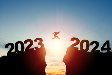 Welcome merry Christmas and happy new year in 2024,Silhouette Man jumping from 2023cliff to 2024 cliff with cloud sky and sunlight. - obrazy, fototapety, plakaty