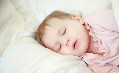 Little cute girl sleeps in her crib. The child is resting. Baby 1 year sleeps on a pillow. Healthy sleep in babies.