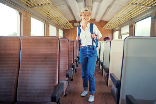 Enjoying trip. Young pretty woman with rucksack traveling by the train.