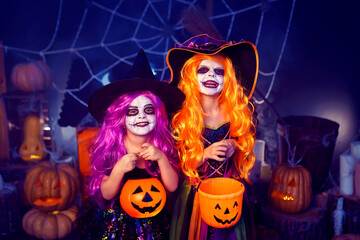 Two kid girls in witches costume scaring, making faces on background decor Halloween. Trick or treat