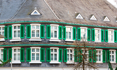 Fassade eines geschieferten Hauses im Bergischen Land mit Fentern und grünen Fensterläden