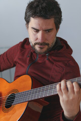 man with beard playing Spanish guitar looking at the strings