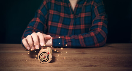 Business achievement goal and objective target concepts. Target icon on round wooden block pointing by businessman hand. Marketing plan in business competition, aiming arrow, future opportunity career