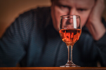 Glass of cognac in front of middle-aged white man. Portrait of man with glass of alcohol