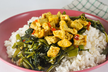 stir-fried water spinach with sliced tofu and white rice served on a red plastic plate with a napkin